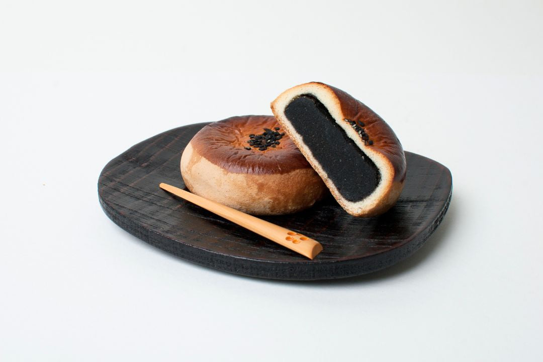 Two black and white bagels on a wooden board with a white background